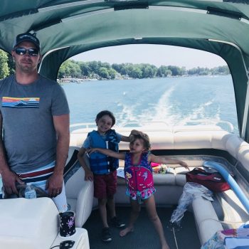 A man and two children enjoying a boat ride together on a sunny day