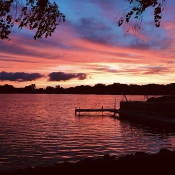 A stunning sunset casts vibrant colors over a tranquil lake