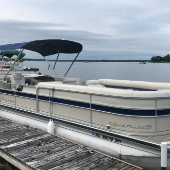 A pontoon boat is moored at a serene lake dock