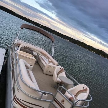 A tranquil scene of a pontoon boat anchored on the water at dusk