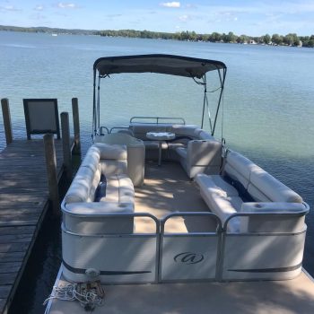 A pontoon boat is anchored peacefully on the calm water, reflecting the surrounding scenery.