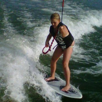 A young girl skillfully wakeboards on the water